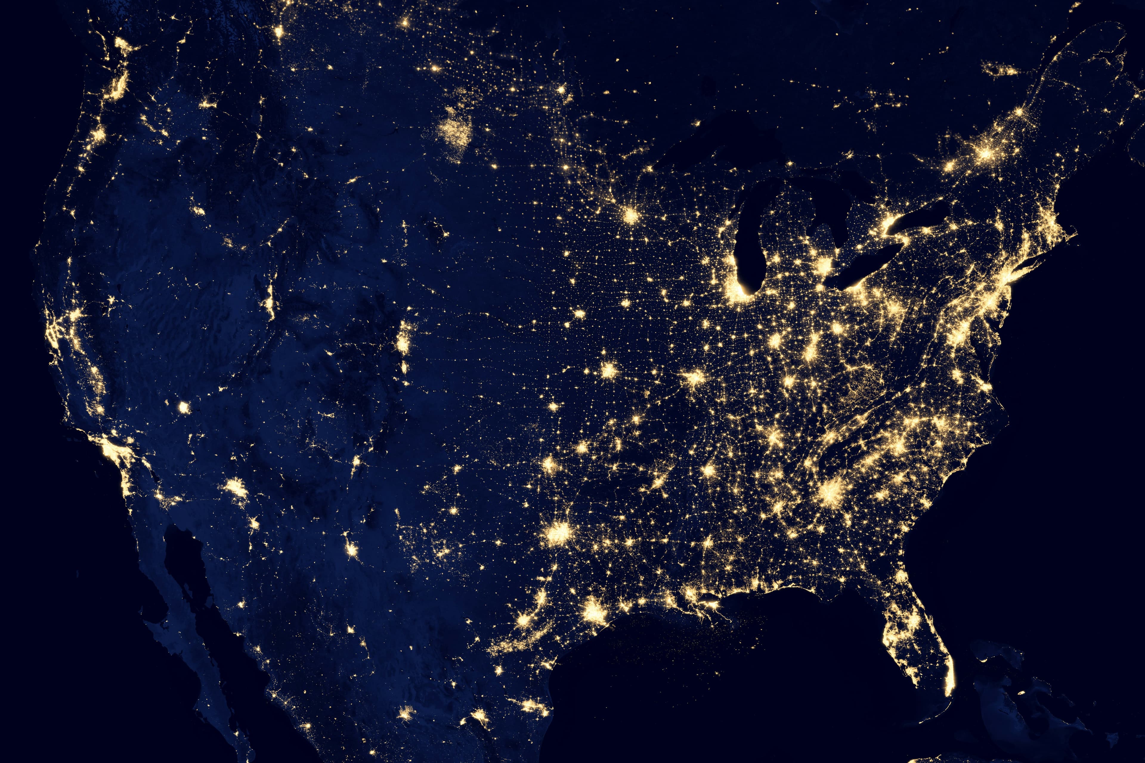 Satellite view of the United States at night, showing city lights connected by a nationwide network