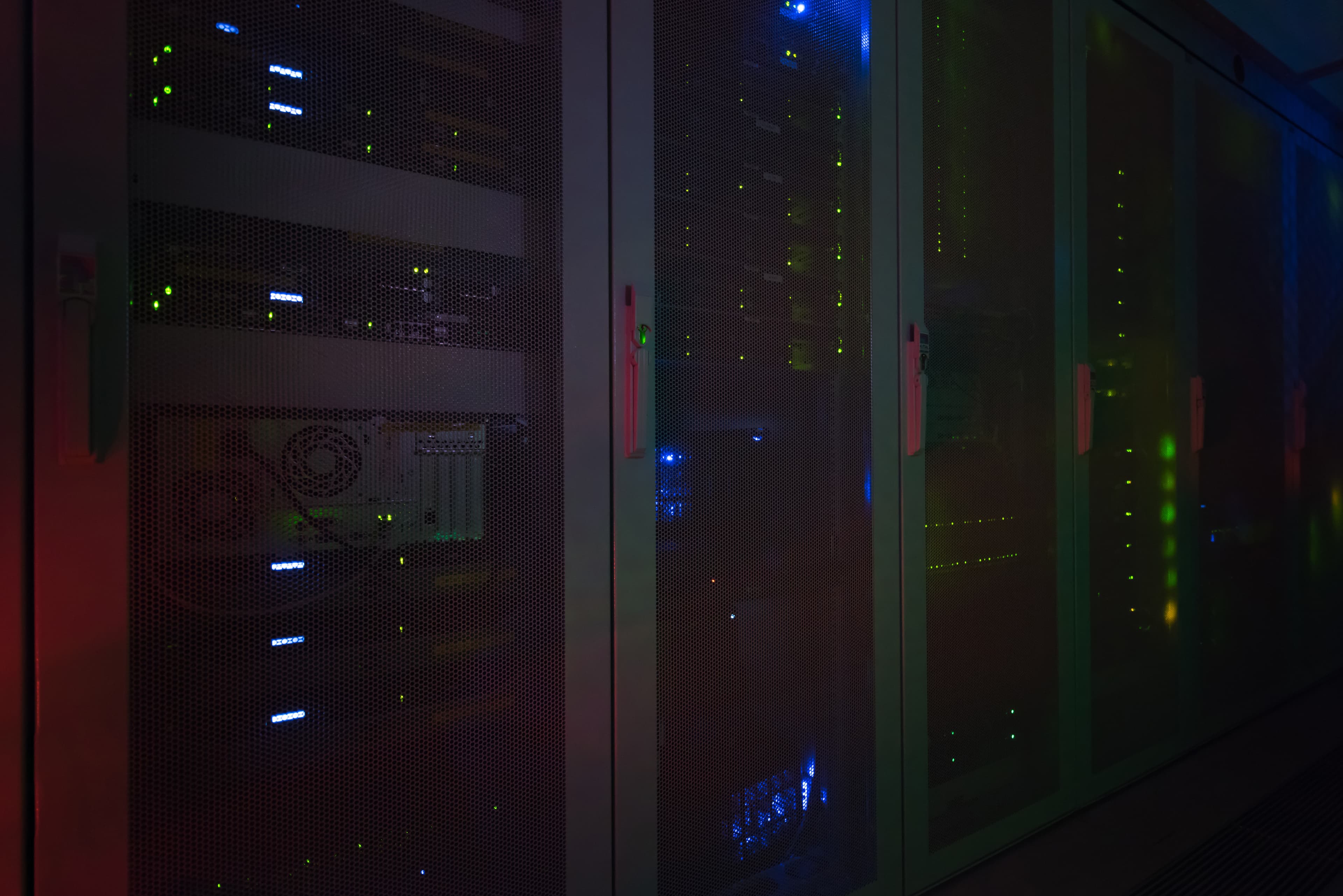 Rows of rack-mounted servers in a dark data center, with green and blue status lights glowing